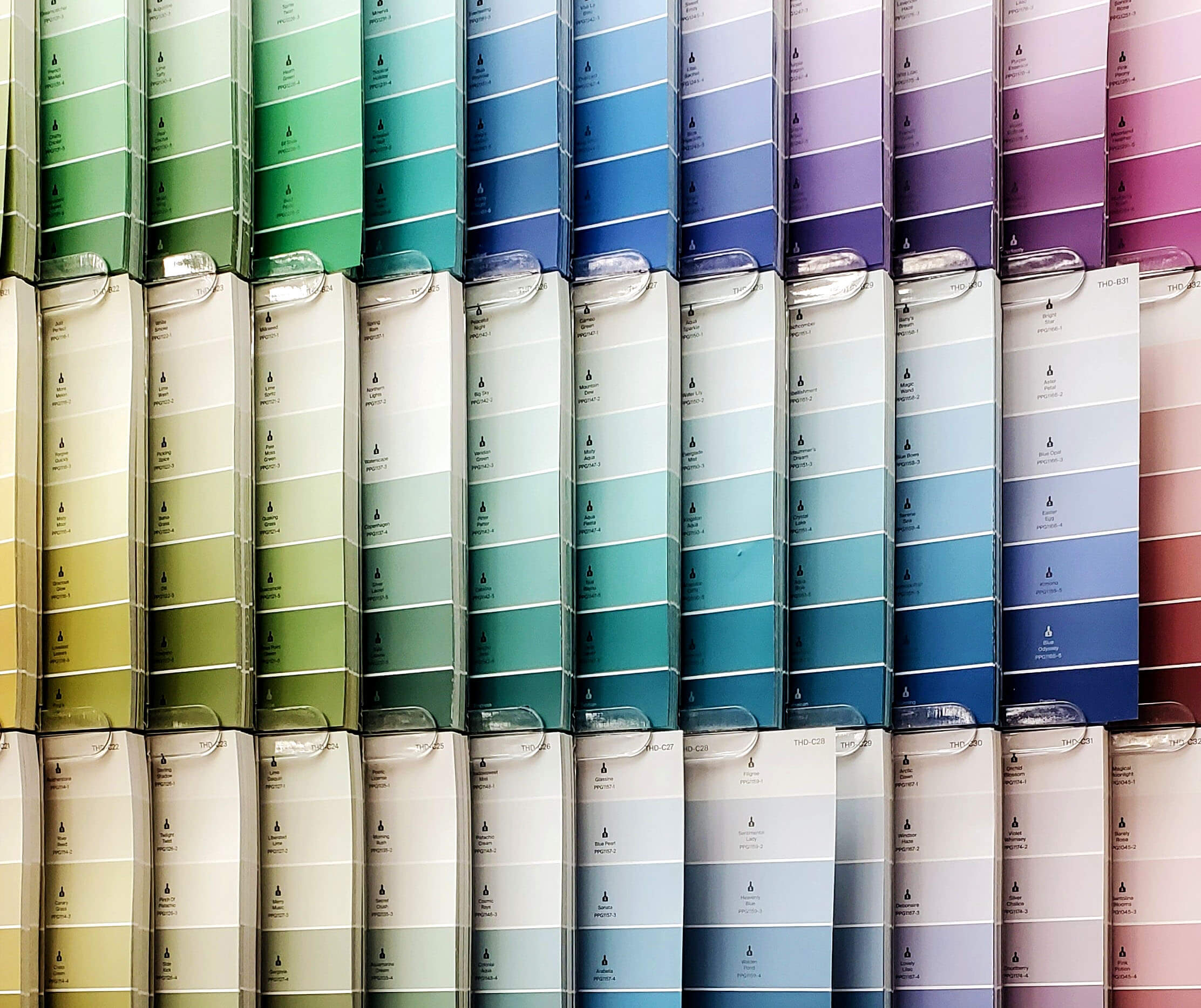 A selection of paint swatch cards arranged by hues to form a rainbow ombre.